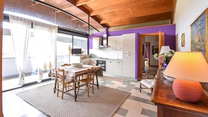 A modern kitchen with wooden cabinets, a dining area with a table and chairs, and a large window with curtains. - Awesome apartment in Cori with WiFi (Cori)