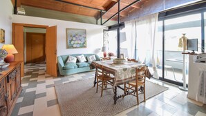 A dining area with a table set for four, a sofa, and a wooden cabinet. - Awesome apartment in Cori with WiFi (Cori)