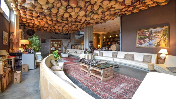 A spacious lobby with a high ceiling adorned with woven baskets, a seating area with a sofa and armchairs, a coffee table, and a large rug. - Awesome apartment in Cori with WiFi (Cori)