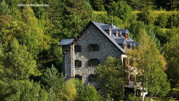 Une maison en pierre entourée d’une forêt dense.