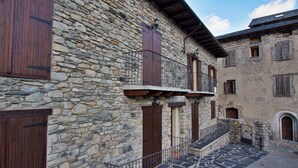 Un bâtiment en pierre avec des volets en bois, un balcon et un escalier menant à un étage supérieur.