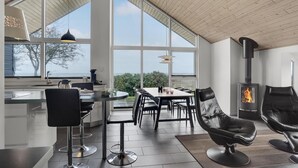 Un amplio espacio habitable con un ventanal grande, una chimenea y una mesa de comedor con sillas.