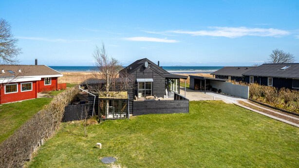 Una casa moderna con una amplia terraza y vistas a la playa.