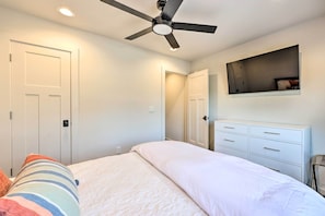 Ein Schlafzimmer mit Bett, Deckenventilator, Kommode und Spiegel.