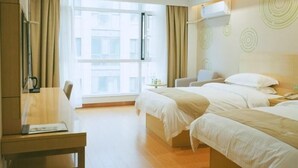 A hotel room with two beds, a desk, and a chair. There is a window with curtains, a wall-mounted air conditioner, and a view of buildings outside. - Greentree Inn Jining Jinyu Road Red Star Macalline Express Hotel (Jining)