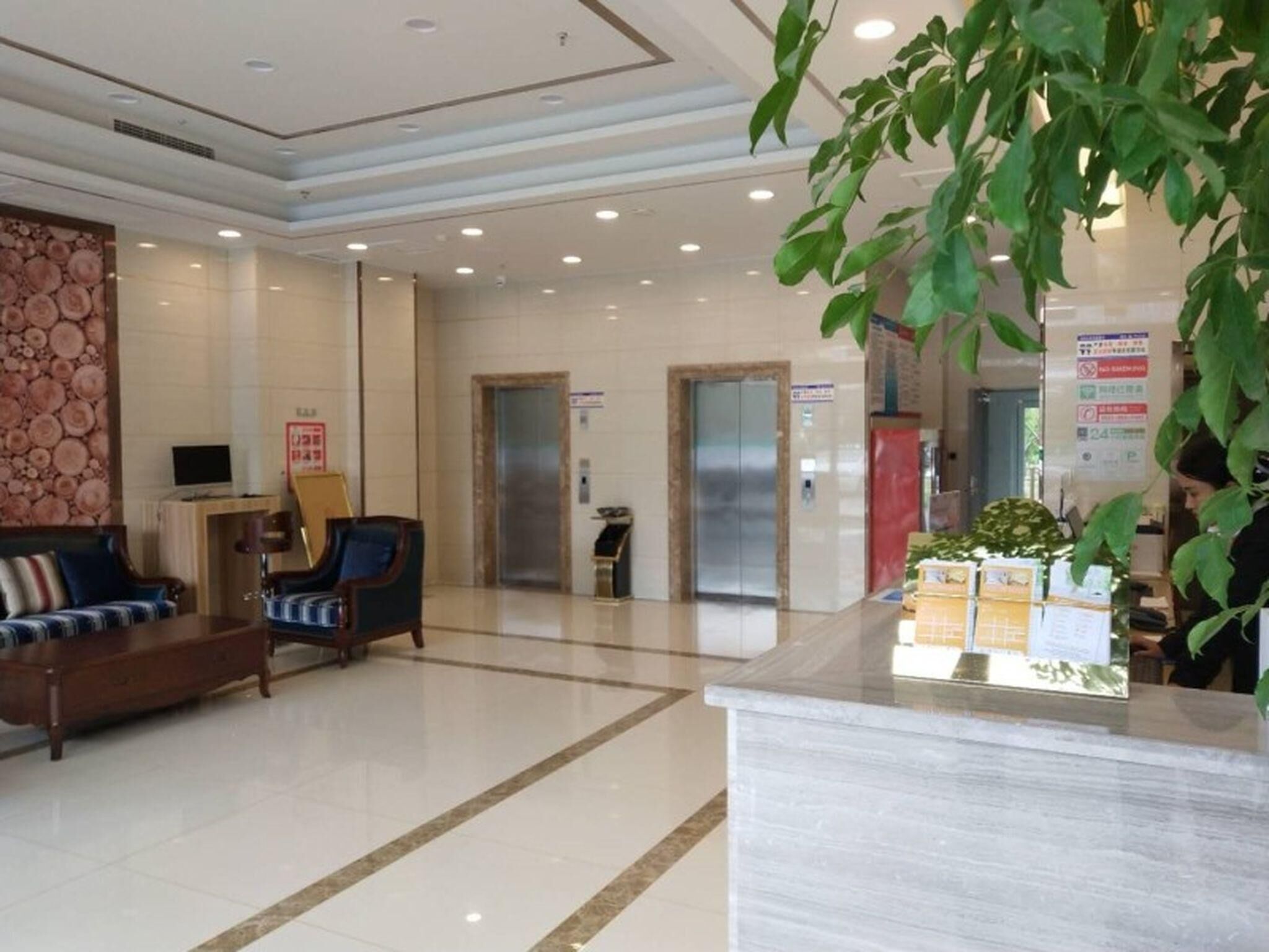 Eine Hotelhalle mit Empfangstresen, Sitzgelegenheiten und Aufzügen.