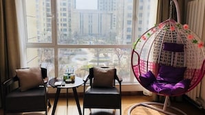 A room with a large window, two chairs, a small table, and a hanging chair with floral decorations. - Greentree Inn Jining Jinyu Road Red Star Macalline Express Hotel (Jining)
