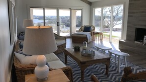 Un salon spacieux doté d’une grande fenêtre, d’une cheminée et offrant une vue sur l’extérieur.