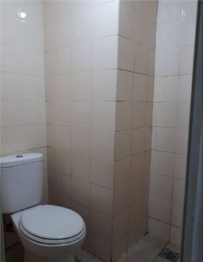 A small, tiled bathroom with a toilet and a shower stall. - Apartmen City Park by GC Realty by Zuzu (Jakarta)