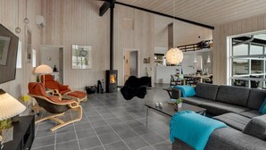 En rummelig stue med pejs, moderne møbler og store vinduer.