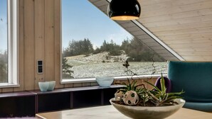 Et moderne interiør med et stort vindue, træloft og en skål med dekorative genstande på et bord.