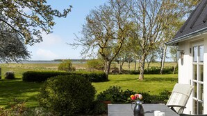 Une terrasse avec une table mise pour le petit-déjeuner, donnant sur un champ verdoyant et des arbres.