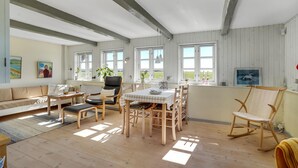 Un espace de vie lumineux et décloisonné, doté d’un plancher en bois, d’une table à manger pour quatre personnes, d’un canapé et d’un fauteuil à bascule.