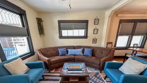 A living room with a brown sectional sofa, two blue armchairs, a wooden coffee table, and a patterned rug.