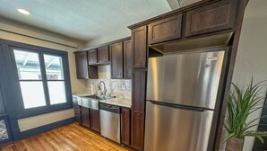 A modern kitchen with dark wooden cabinets, stainless steel appliances, and a large window providing natural light.