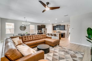 A modern living room with a sectional sofa, a round coffee table, and a ceiling fan.