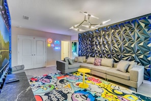 A modern living room with a sectional sofa, a colorful rug, and a geometric wall panel.
