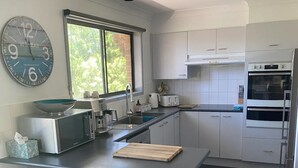 Een moderne keuken met een centraal eiland, barkrukken, een klok en een raam met uitzicht.
