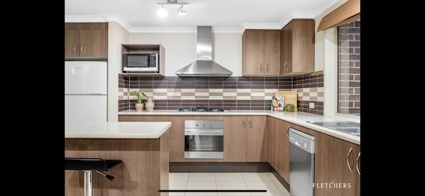 Enjoy cooking in this well-equipped kitchen with a microwave, stainless steel range hood, and dishwasher.