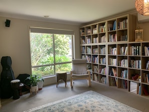 Relax in comfort with a view of lush greenery from the large window, accompanied by a cozy reading nook and a bookshelf.