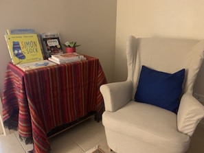 Cozy reading nook with a table, books, and a comfortable armchair.
