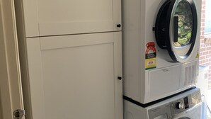 Una lavadora y secadora apiladas, con una etiqueta visible de calificación energética y una cesta encima.