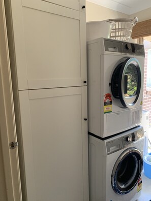 A stacked washer and dryer unit with a visible energy rating sticker and a basket on top. - Doreen Gem (Doreen)