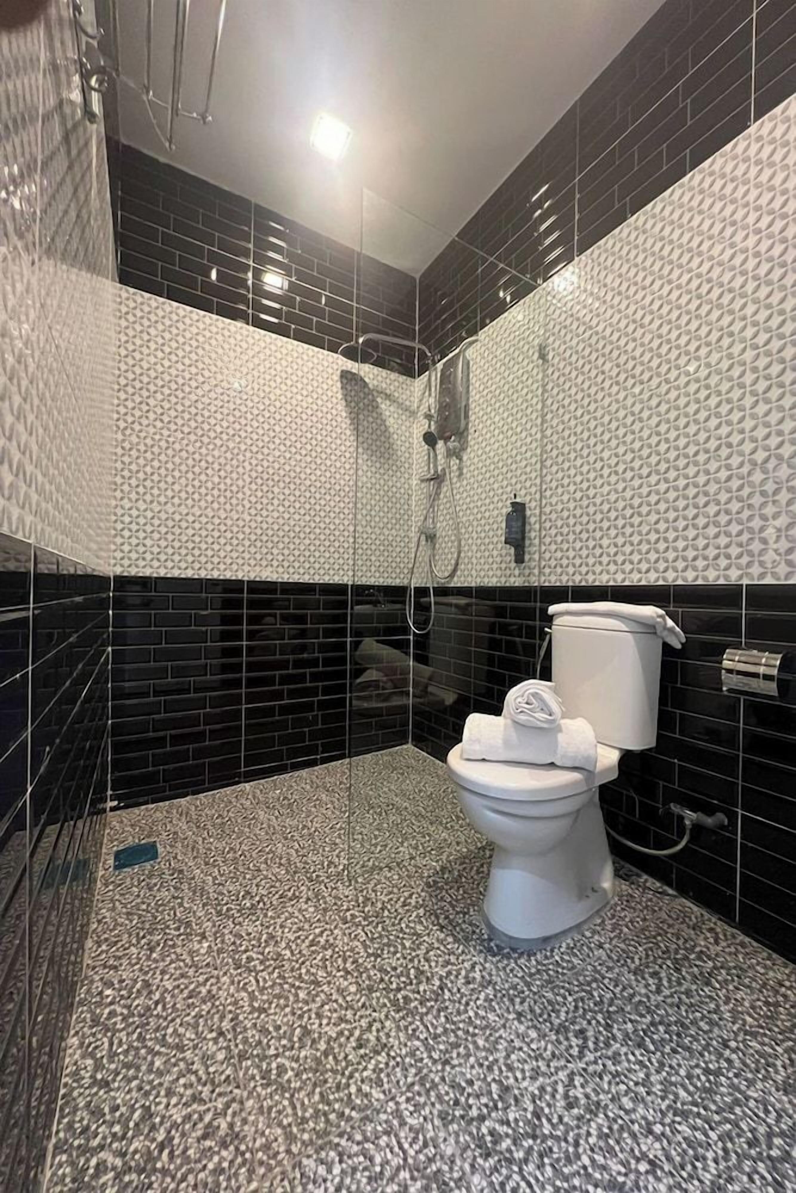 A modern bathroom with a shower, toilet, and a tiled floor.