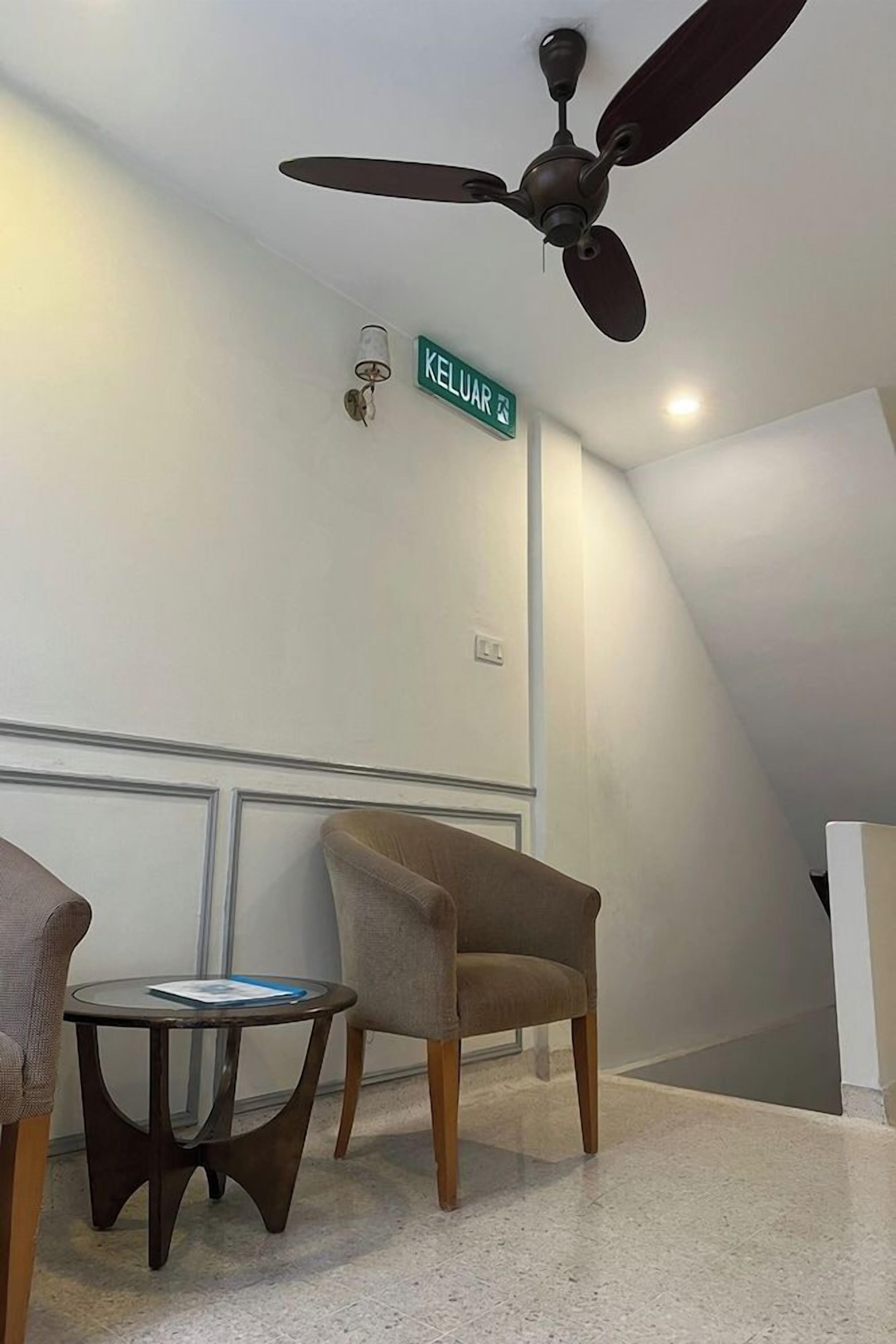 A room with a ceiling fan, a chair, a small table, and a wall sign.