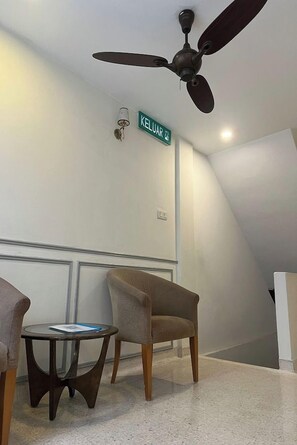 A room with a ceiling fan, a chair, a small table, and a wall sign. - M S Hotel Tengku Kelana KTM Klang (Klang)