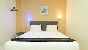 A neatly made bed with white linens and a dark blanket, a wall-mounted light fixture, and a simple artwork on the wall. - M S Hotel Tengku Kelana KTM Klang (Klang)