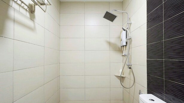 A small, tiled bathroom with a shower, toilet, and a dark tiled accent wall. - M S Hotel Tengku Kelana KTM Klang (Klang)