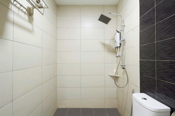 A small, tiled bathroom with a shower, toilet, and a dark tiled accent wall. - M S Hotel Tengku Kelana KTM Klang (Klang)