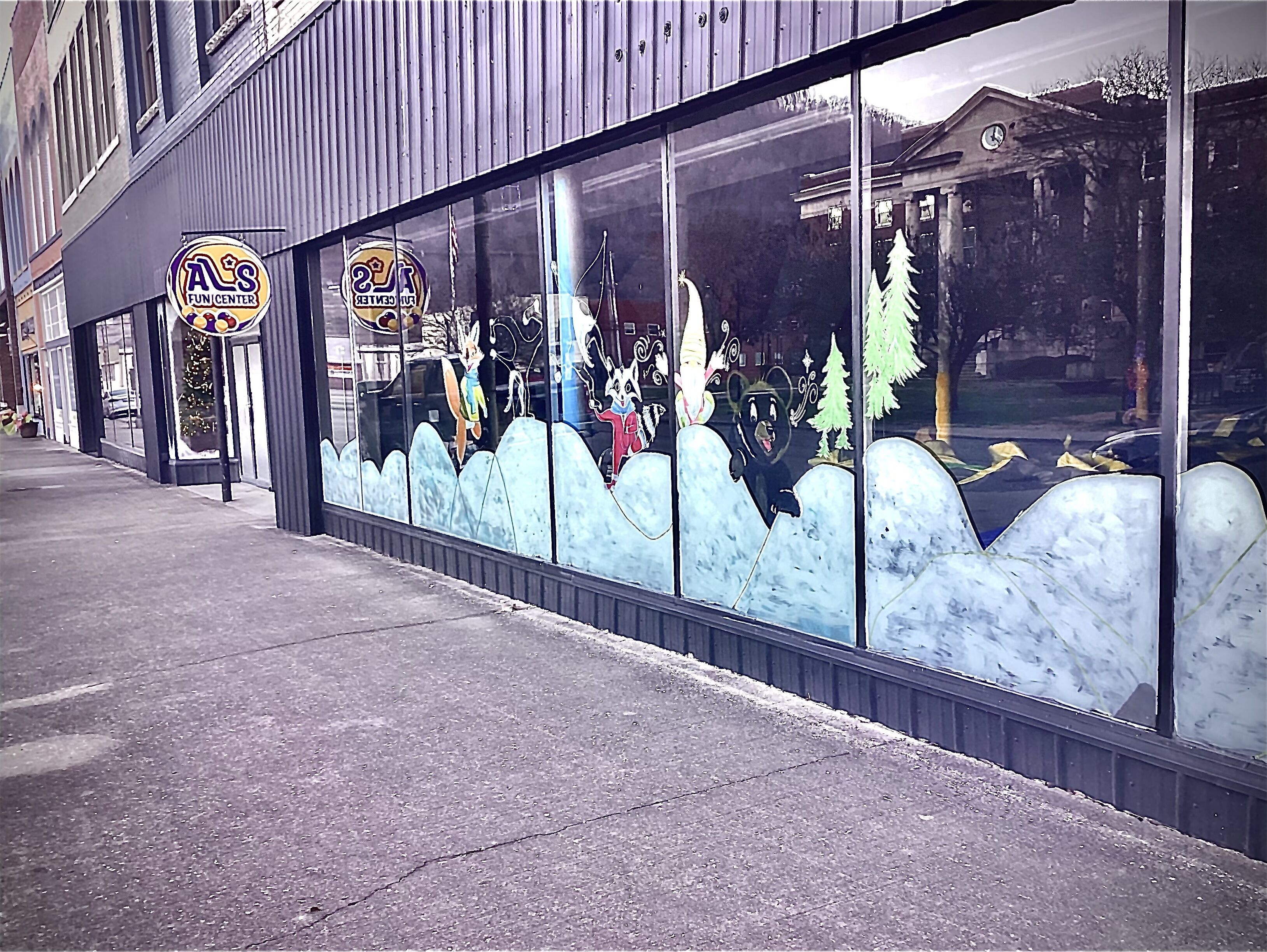 A storefront with a large window display featuring cartoon characters and a Christmas tree.