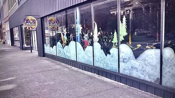 A storefront with a large window display featuring cartoon characters and a Christmas tree.