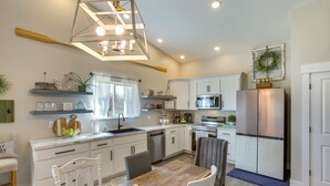 Una cocina moderna con armarios blancos, una mesa de comedor de madera y una lámpara colgante.