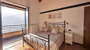 Une chambre à coucher avec un lit, des tables de chevet, une fenêtre donnant sur un paysage agréable et une porte.