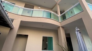 Un immeuble à plusieurs étages, doté de balcons, d’une petite fenêtre et d’une plante en pot.