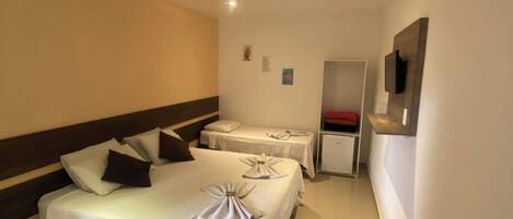 A hotel room with two beds, a TV mounted on the wall, and a small cabinet.