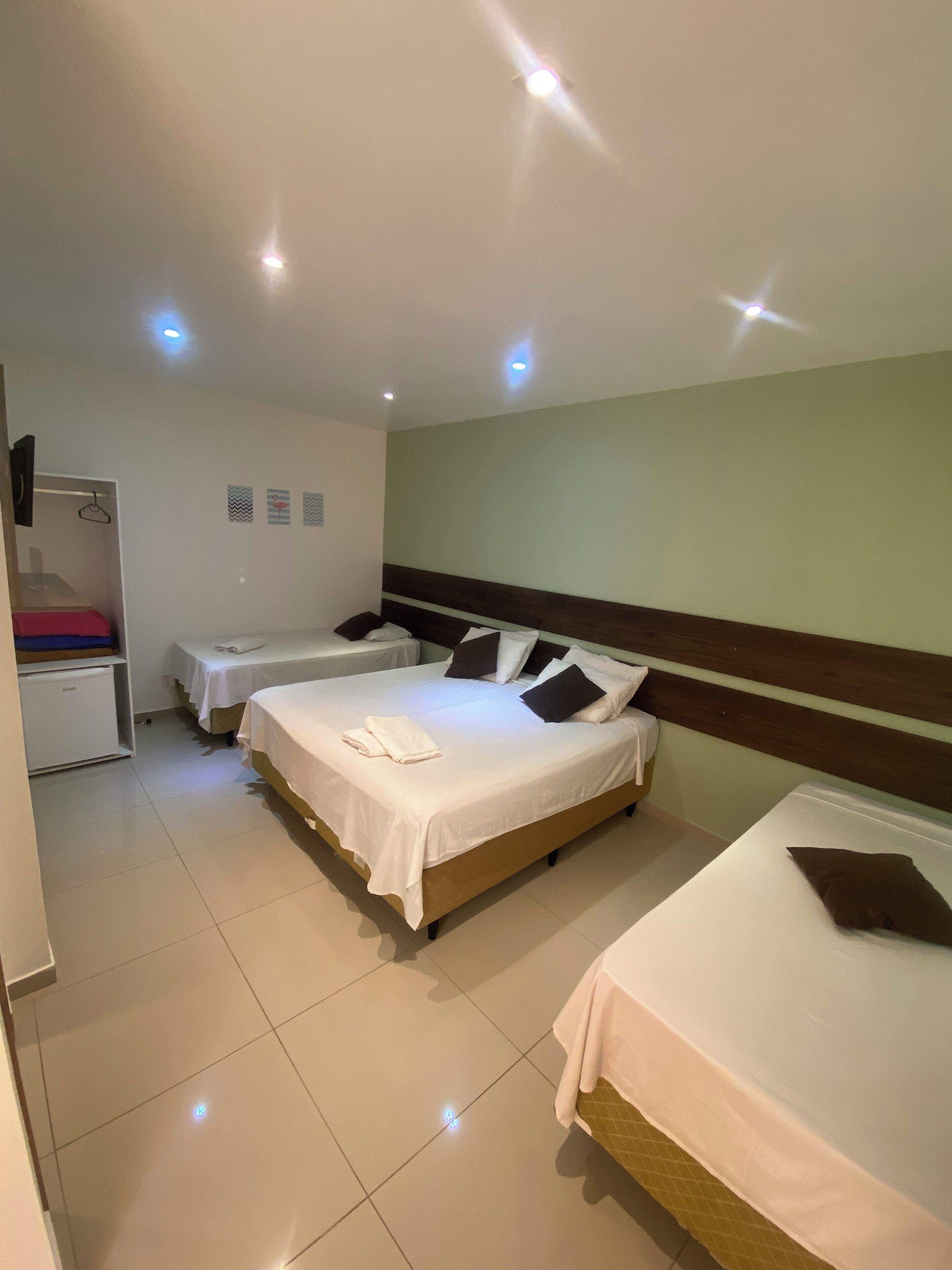 A hotel room with two beds, a small desk, and a wardrobe.