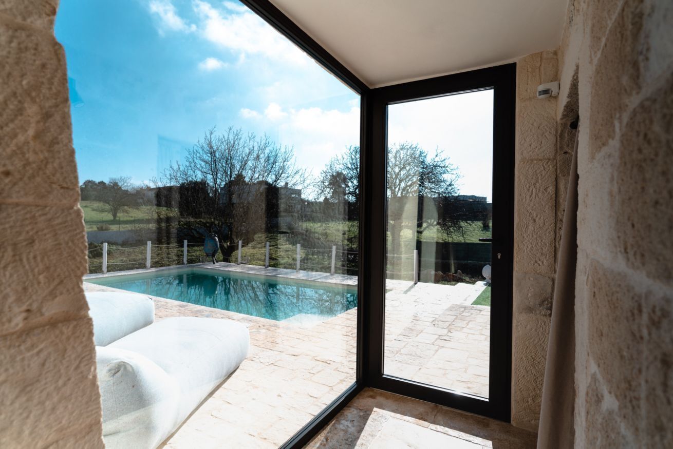 A modern room with a large glass door leading to an outdoor swimming pool area.