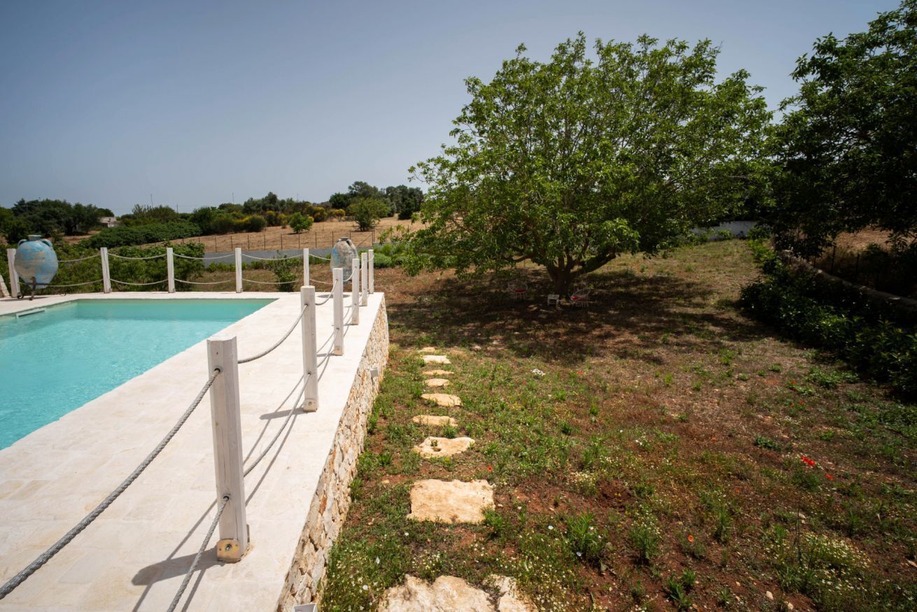 Une piscine avec un chemin de pierre menant à un arbre.