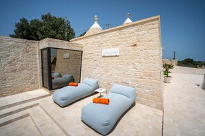 Una habitación con paredes de piedra, dos sofás azul claro, una pequeña mesa y un ventanal con acceso a un balcón.