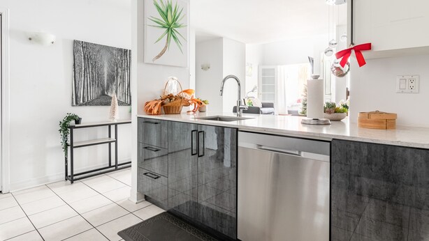 Een moderne keuken met grijze kastjes, een RVS vaatwasser en een wit aanrecht.