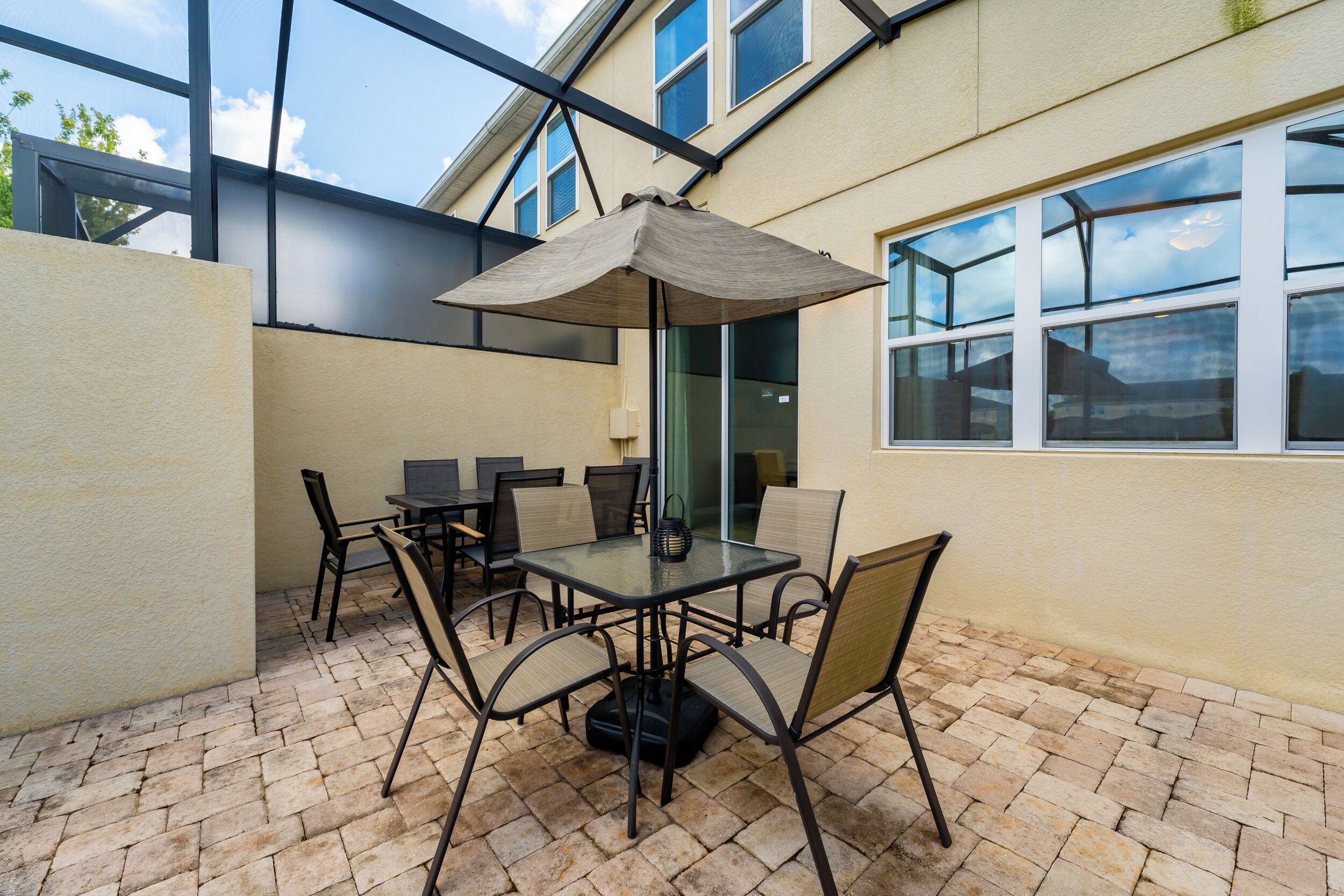 Un patio con mesa y sillas, una sombrilla grande y vistas a un edificio con ventanas.