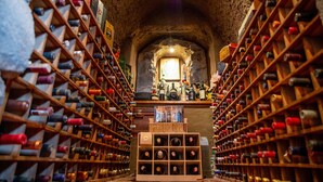 A wine cellar with wooden racks filled with wine bottles, a central display case, and a stone archway. - Hotel Boutique La Casona de La Moreria (Amaguaña)