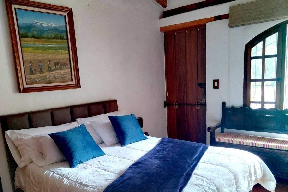 Ein Schlafzimmer mit einem Bett, einer Holzbalkendecke, einer Tür und einem Fenster.