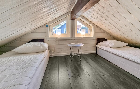 A small attic bedroom with two single beds, a small table, and a skylight. - Lovely home in Tanumshede with kitchen (Tanumshede)