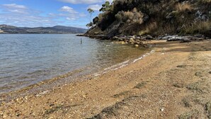 A beach with clear water, pebbles, and a rocky shoreline.
