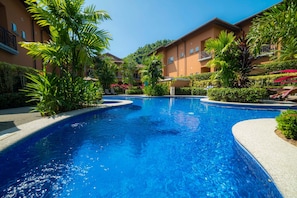 A swimming pool surrounded by lush greenery and multi-story buildings.